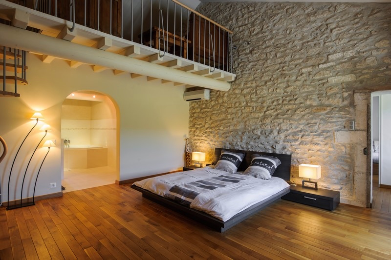 Chambre avec mur en pierre et mezzanine